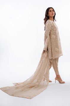 A short beige khaddi corduroy shirt with aari and tilla embroidery is paired with a matching worked organza dupatta. Playful tassel detailing complements the shirt and an embroidered rawsilk shalwar completes the look. Model Height is 5'2 and Shirt Length is 35' Designer Naqshi Organza Kurta, Designer Naqshi Lawn Suit In Organza, Beige Semi-stitched Sets With Sheer Dupatta, Beige Organza Sets With Intricate Embroidery, Beige Silk Set With Sheer Dupatta, Semi-stitched Beige Kurta With Sheer Dupatta, Beige Georgette Sets With Sheer Dupatta, Eid Tissue Silk Lawn Suit With Naqshi, Beige Kurta With Resham Embroidery In Georgette