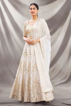 Ivory lehenga with all-over intricate mirror embellishments. Comes with round neckline blouse and dupatta.
Component: 3
Embroidered
Neckline: Round
Sleeve Length: Half
Fabric: Dupion Raw Silk
Color: White
Deep U neck at the back with tie-up
Embroidered dupatta
Closure: 
Blouse: Hook closure at the back
Lehenga: Drawstring with latkans - Aza Fashions Festive Off-white Gota Work Sets, Off White Gota Work Sets For Diwali, White Pre-draped Saree With Gota Work For Navratri, White Kundan Sharara With Intricate Embroidery, Off White Sets For Reception On Eid, Off White Sets For Eid Reception, Off White Sets For Reception At Eid, Off White Sets For Reception And Eid, Festive Off-white Set With Dupatta