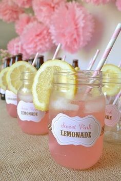 there are lemonade in mason jars with straws on the top and pink flowers behind them