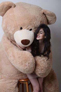 a woman is hugging a giant teddy bear