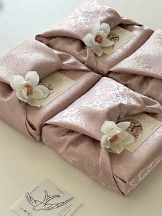 four wrapped gift bags with flowers on them sitting on a table top next to a card