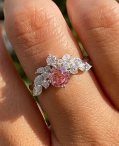 a woman's hand with a pink and white diamond ring on top of it