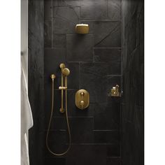 a bathroom with black tile and gold fixtures on the shower head, hand held by a brass faucet