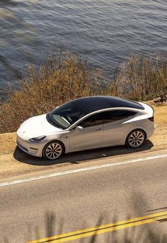 an electric car is parked on the side of the road by the water's edge