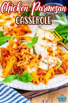 chicken parmesan casserole is served on a white plate with basil leaves