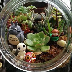 a glass jar filled with plants and small figurines