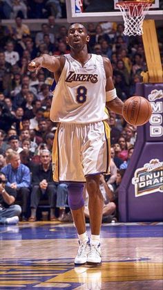 a basketball player holding a ball in his right hand while standing on a court with people watching