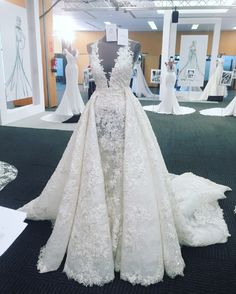 a white wedding dress on display in a room with mannequins and dresses