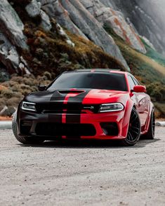 a red and black car parked in front of a mountain