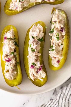 four stuffed peppers with crab salad on them sitting on a white plate next to two lemons