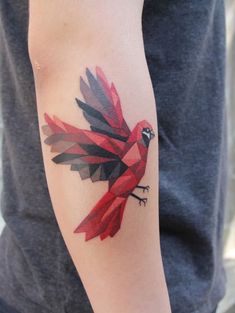 a red and black bird tattoo on the arm