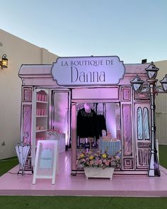 a pink display with clothes and flowers in front of the store's entrance at night