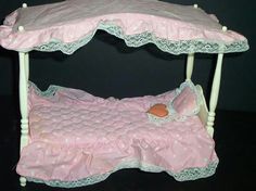 a doll bed with pink sheets and white trim