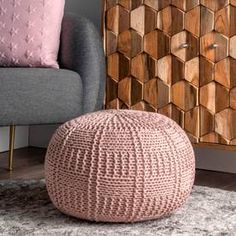 a pink pouffle sitting on top of a rug next to a gray chair