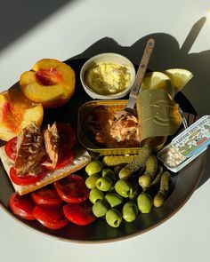 a plate with olives, tomatoes, bread, and other food items on it