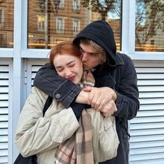 a man and woman hugging each other in front of a building