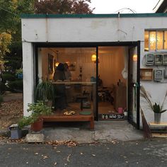 a man is sitting in the window of a shop with plants and other things on display