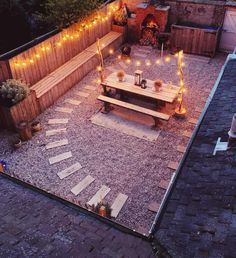 an outdoor patio with lights on the side and table in the middle surrounded by gravel