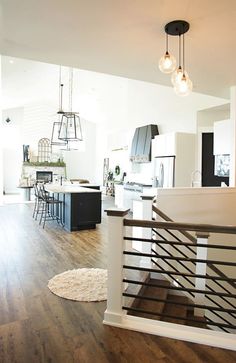 an open floor plan with white walls and wood floors, black accents and pendant lights