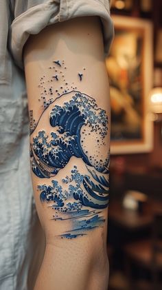 a person with a tattoo on their leg that has an image of a wave in the ocean