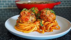 spaghetti and meatballs are served on a white plate