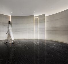 a woman walking through an empty room with columns