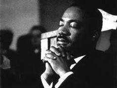 a black and white photo of a man in a suit holding his hands together to his chest