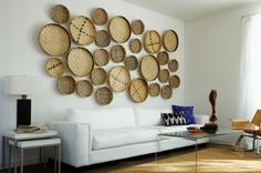 a living room with a white couch and lots of wicker baskets on the wall