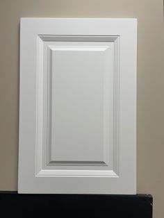 a close up of a white frame on a wall with a black shelf below it