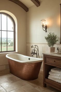 a bathroom with a large window and a copper bathtub in it's center