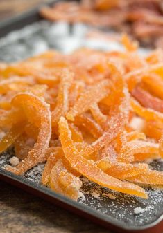 orange peels are sitting on a plate with powdered sugar and bacon in the background