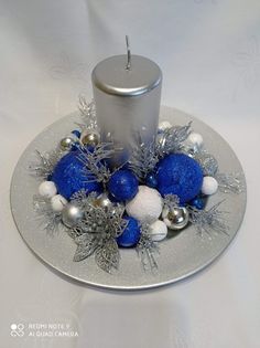 a candle on a silver plate with blue and white ornaments