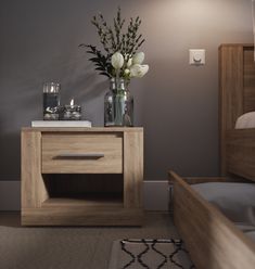 a vase with flowers sitting on top of a wooden table next to a bed in a bedroom