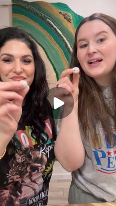 two women sitting at a table with toothbrushes in their hands