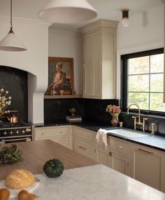 a kitchen with marble counter tops and white cabinets, along with a painting on the wall