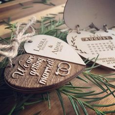 two wooden heart shaped tags on top of a table next to pine needles and twine