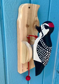 a wood carving of a bird on a blue door with a red string attached to it