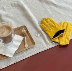 a wooden tray topped with a cup of coffee next to a yellow glove