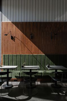 three tables and two chairs in front of a wall with wood paneling on it