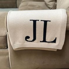 a blanket with the letter j on it sitting on top of a couch next to pillows