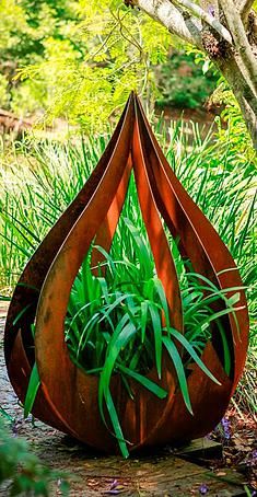 an outdoor sculpture made out of wood and metal with plants growing in it's center