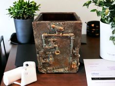 a wooden box sitting on top of a table next to a phone and some plants