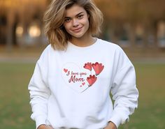 a woman in a white sweatshirt with hearts on it and the words i love you mom