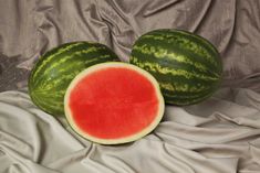 two pieces of watermelon sitting on top of a white cloth next to each other