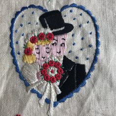 a close up of a wedding embroidered on a piece of cloth with flowers and hearts