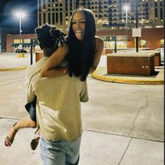 a woman is hugging a man on the street at night with buildings in the background