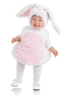 a baby in a bunny costume is smiling and holding a large pink heart shaped object