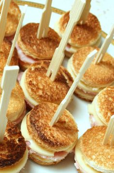 some food is being displayed on a plate with toothpicks in the shape of sandwiches