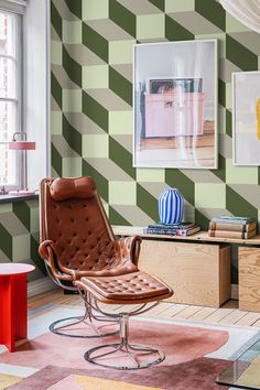 a living room with green and white wallpaper, brown leather chair and red table