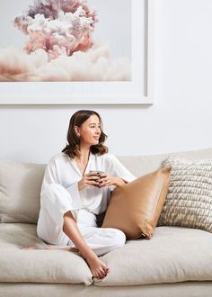 a woman sitting on a couch holding a pillow